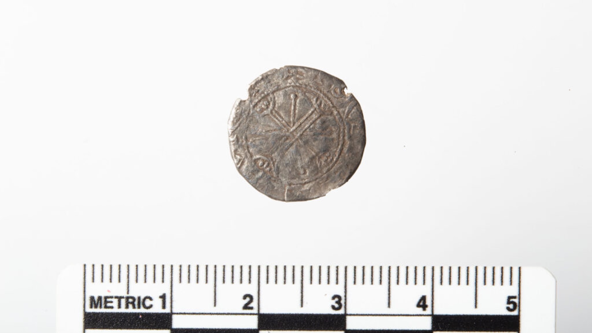 Old Viking silver coin minted by King Magnus Barefoot with ruler for scale