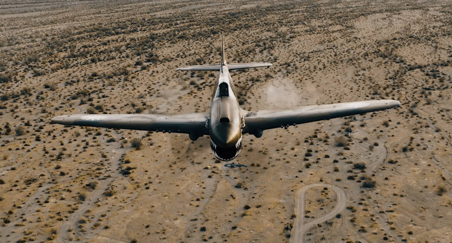 Front view of P-40 Warhawk in flight above desert