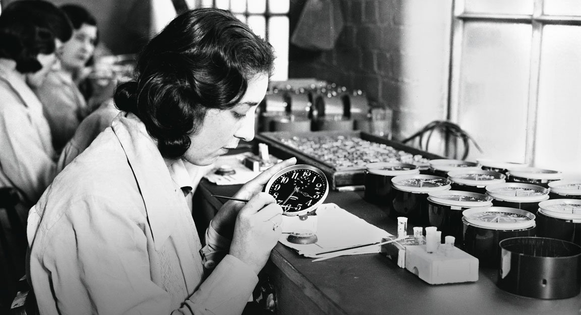 A woman in historical photograph paints a watch dial.