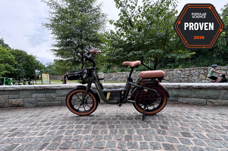 The Segway MUXI cargo e-bike sitting on cobblestones beside the Mount Vernon bike path at the entrance to Theodore Roosevelt Island. The PopSci Priven badge is shown in the top right corner.
