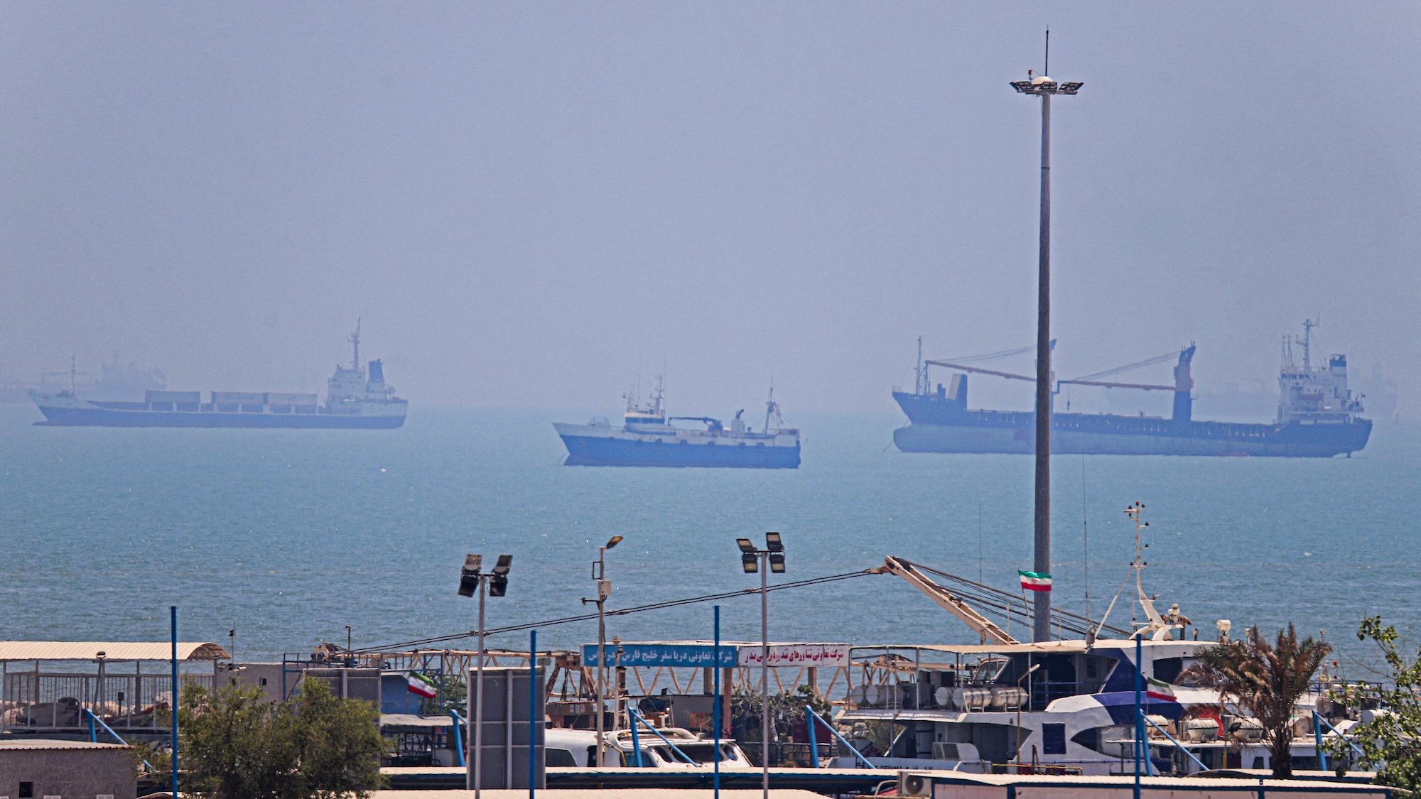 In this picture obtained from Iran's ISNA news agency on June 18, 2026, vessels are seen anchored in Bandar Abbas along the Strait of Hormuz. Oil prices tumbled after Trump and his Iranian counterpart separately signed their accord to end the Middle East war, with the Strait of Hormuz to reopen but two months of negotiations lying ahead. (Photo by AMIRHOSSEIN KHORGOOEI / ISNA / AFP) /