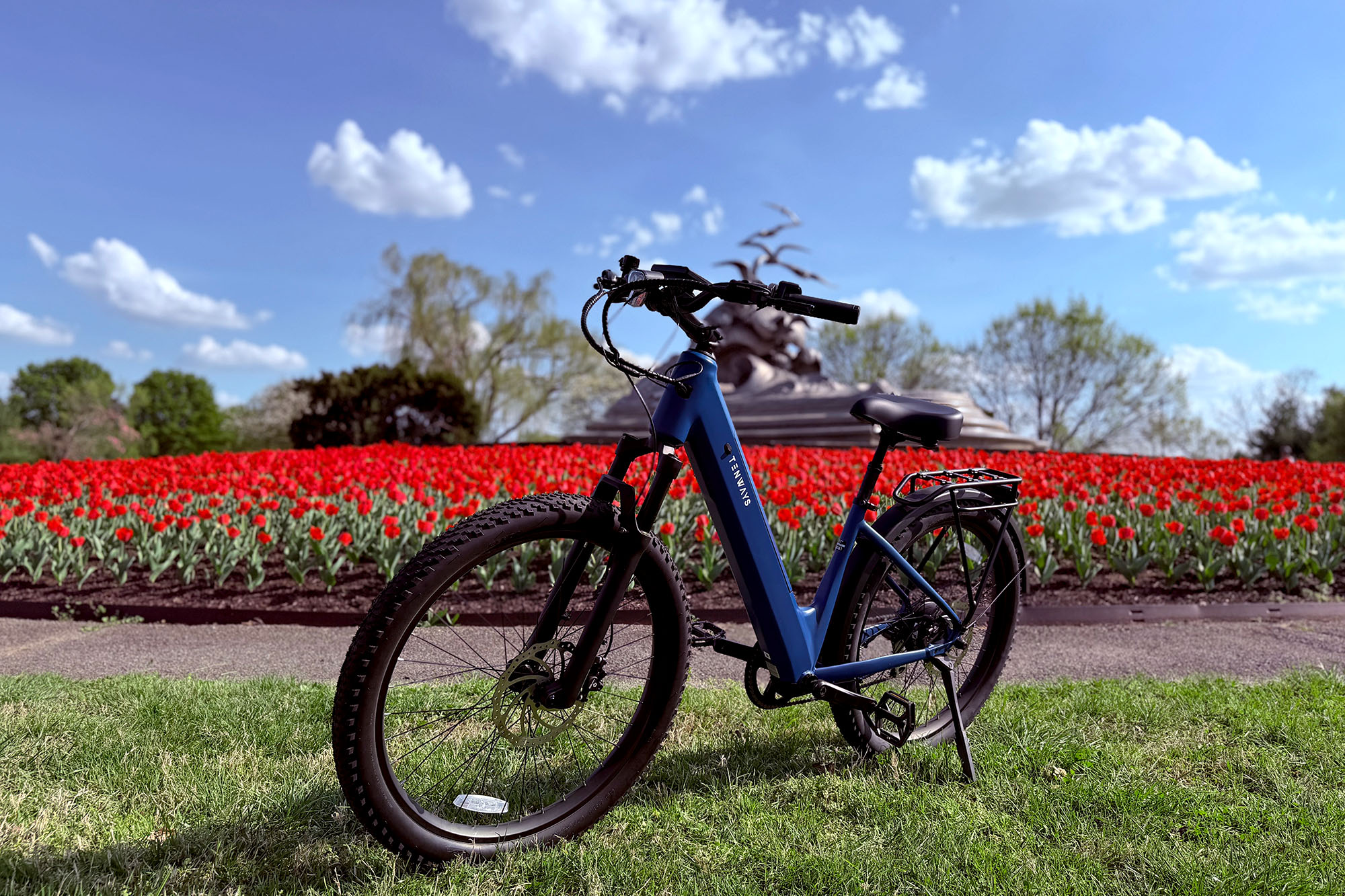 A Sapphire Blue Tenways Wayfarer commuter ebike in front of red tulips at the Lady Bird Johnson Memorial