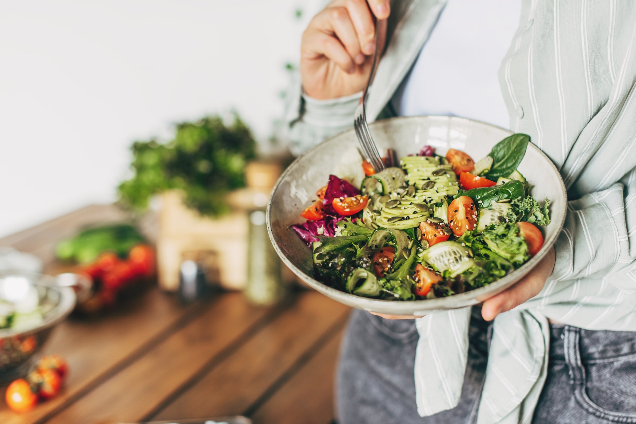 Woman eating delicious superfood salad ingredients with fork.