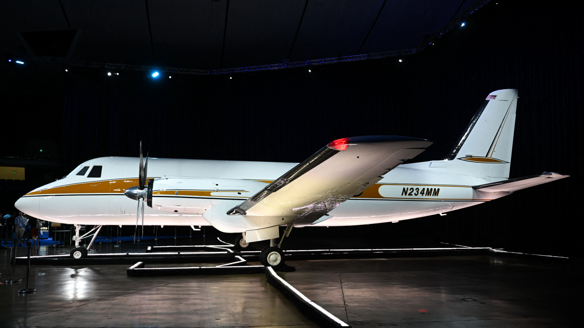 a white plane with a yellow stripe on the side on display inside