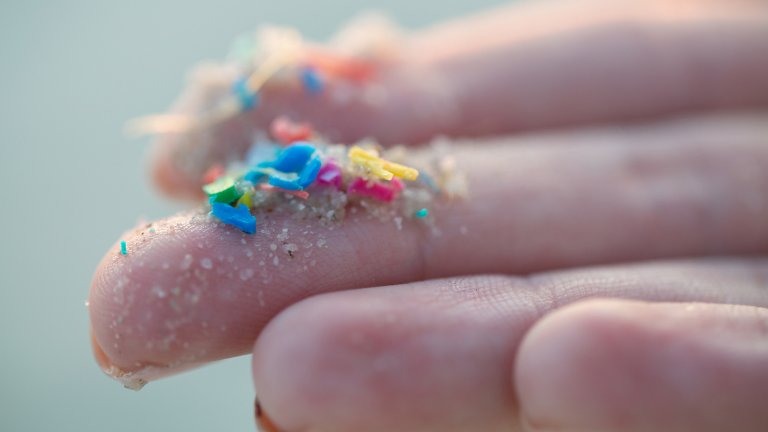 Close up of researcher holding small pieces of micro plastics on finger tips.