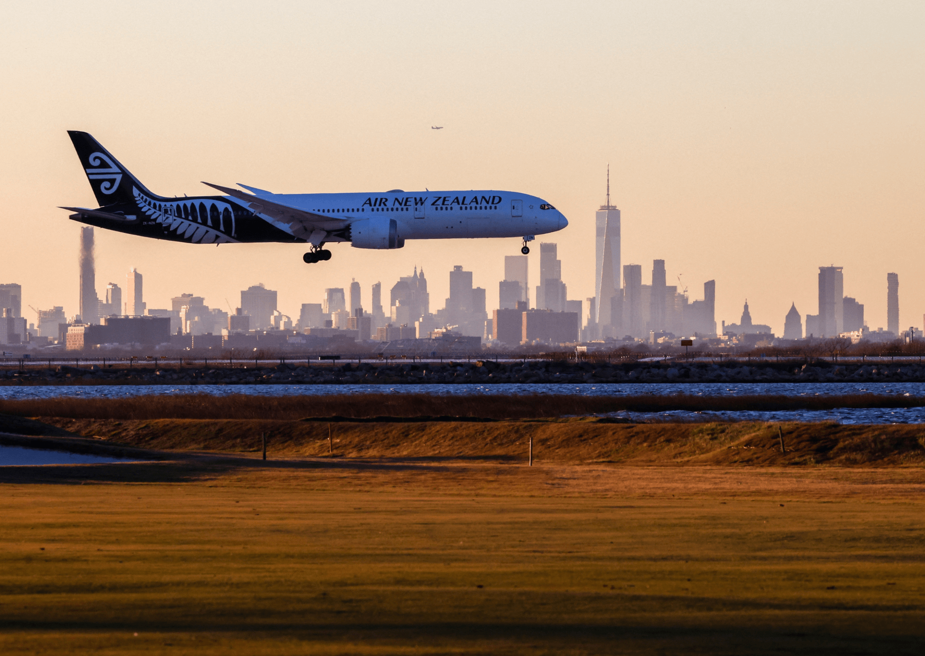 an air new zealand plane landing with the new york city skyline in the background