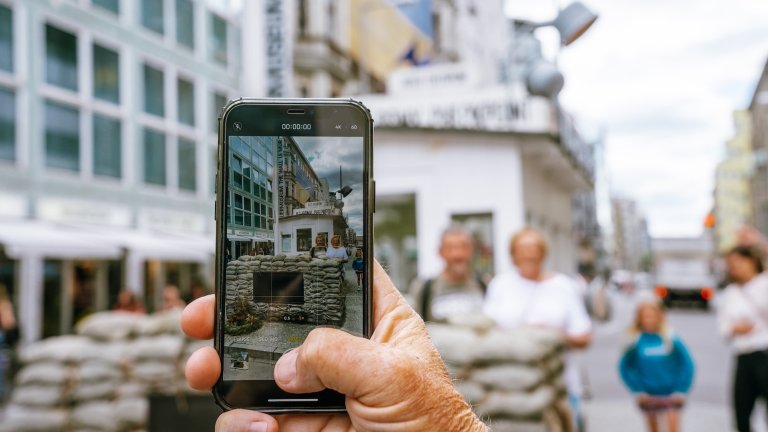 Person taking a photo with an iphone at Check Point Charlie in Berlin, Germany