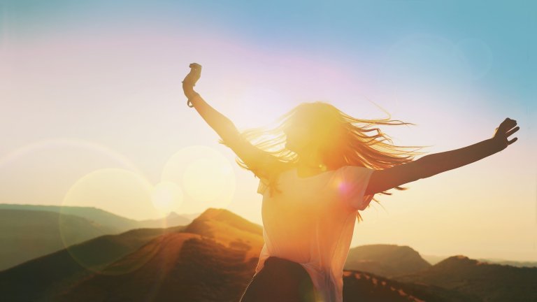 woman with outstretched arms dancing in sunlight
