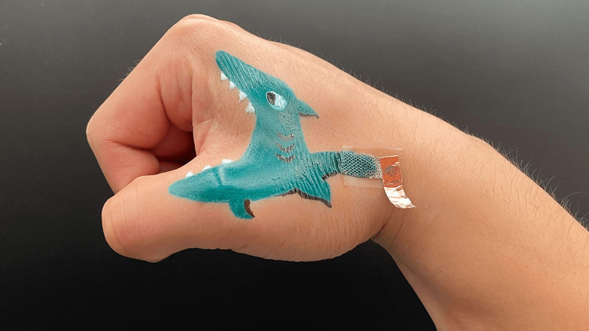 a painted shark on a hand connected to a sensor