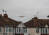 a singapore airlines plane beginning its descent between two houses with red roofs