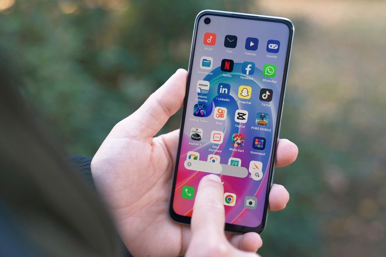 A hand holding an Android smartphone and touching its screen