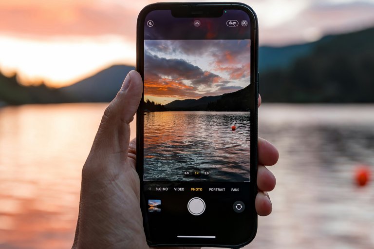An iPhone's Camera app shown capturing the sun setting on a lake