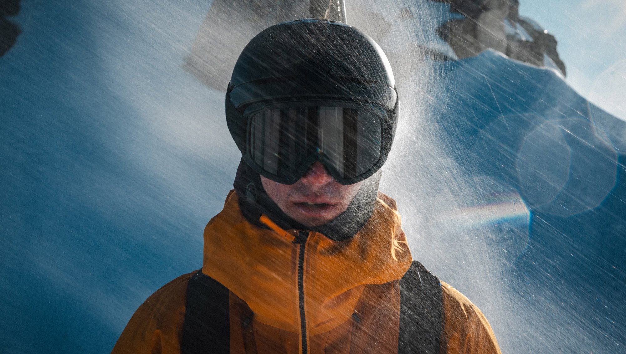 A person wearing a helmet and goggles getting hammered with snow wearing the Arc'teryx Sperro SV jacket