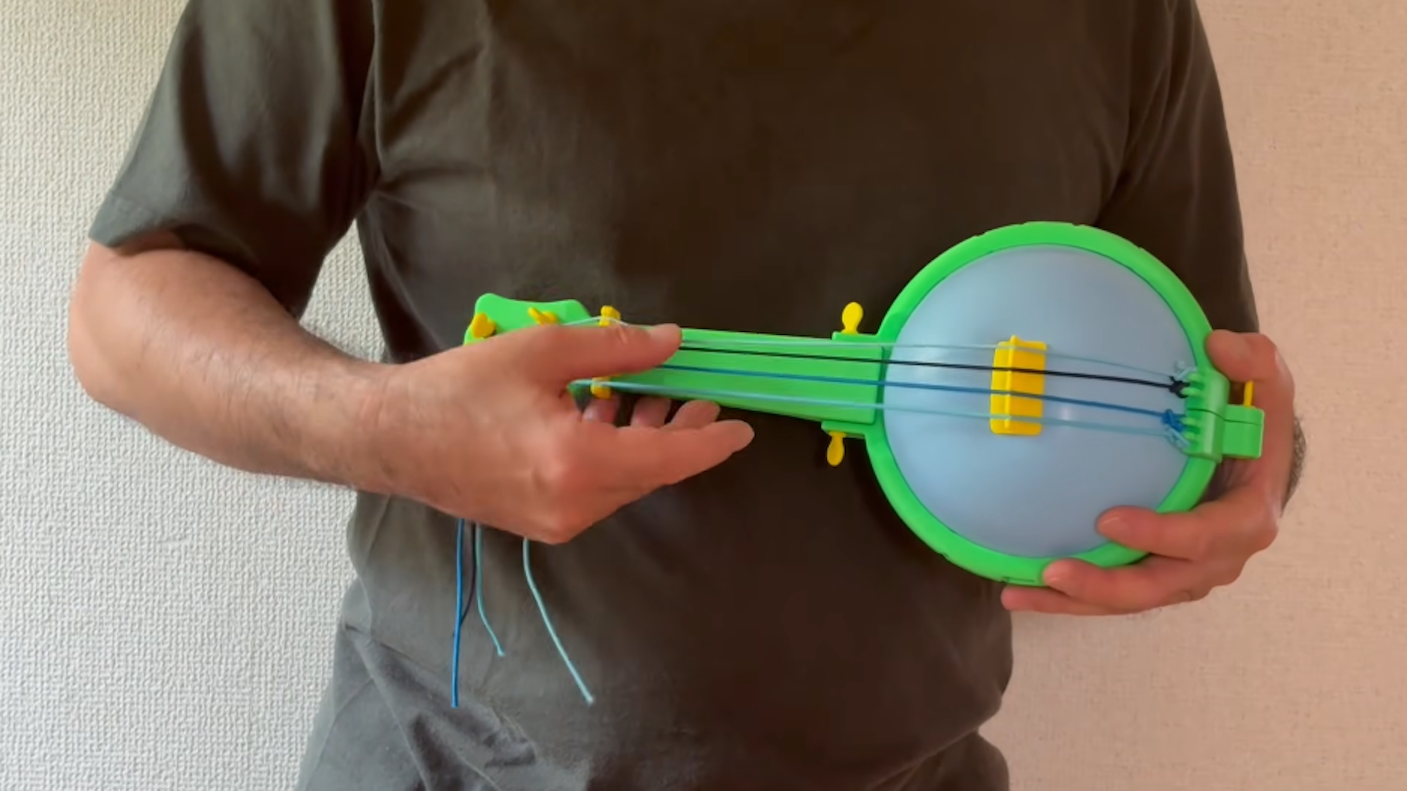 Man holding 3D printed toy banjo that uses balloon as sound board
