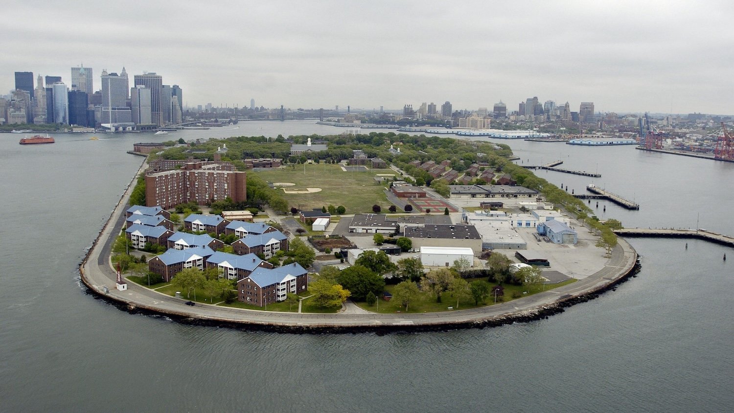 New York, UNITED STATES: Governors Island is pictured 11 May 2006 in New York harbor with lower Manhattan (L) in background. According to the National Park Service, Governors Island was the command headquarters and military post for the United States Army from 1794 until 1966. From 1966 to 1996 it was the US Coast Guard?s largest and most complex installation. In 2003, the island was sold and transferred to two parties: 22 acres, designated as the Governors Island National Monument, to the US Secretary of the Interior, and managed by the National Park Service; and 150 acres to the Governors Island Preservation and Education Corporation, a corporation formed jointly by the State and City of New York. Today, city, state and federal agencies are in the planning stages of converting this former military installation into new public parkland. AFP PHOTO/Stan HONDA (Photo credit should read STAN HONDA/AFP via Getty Images)