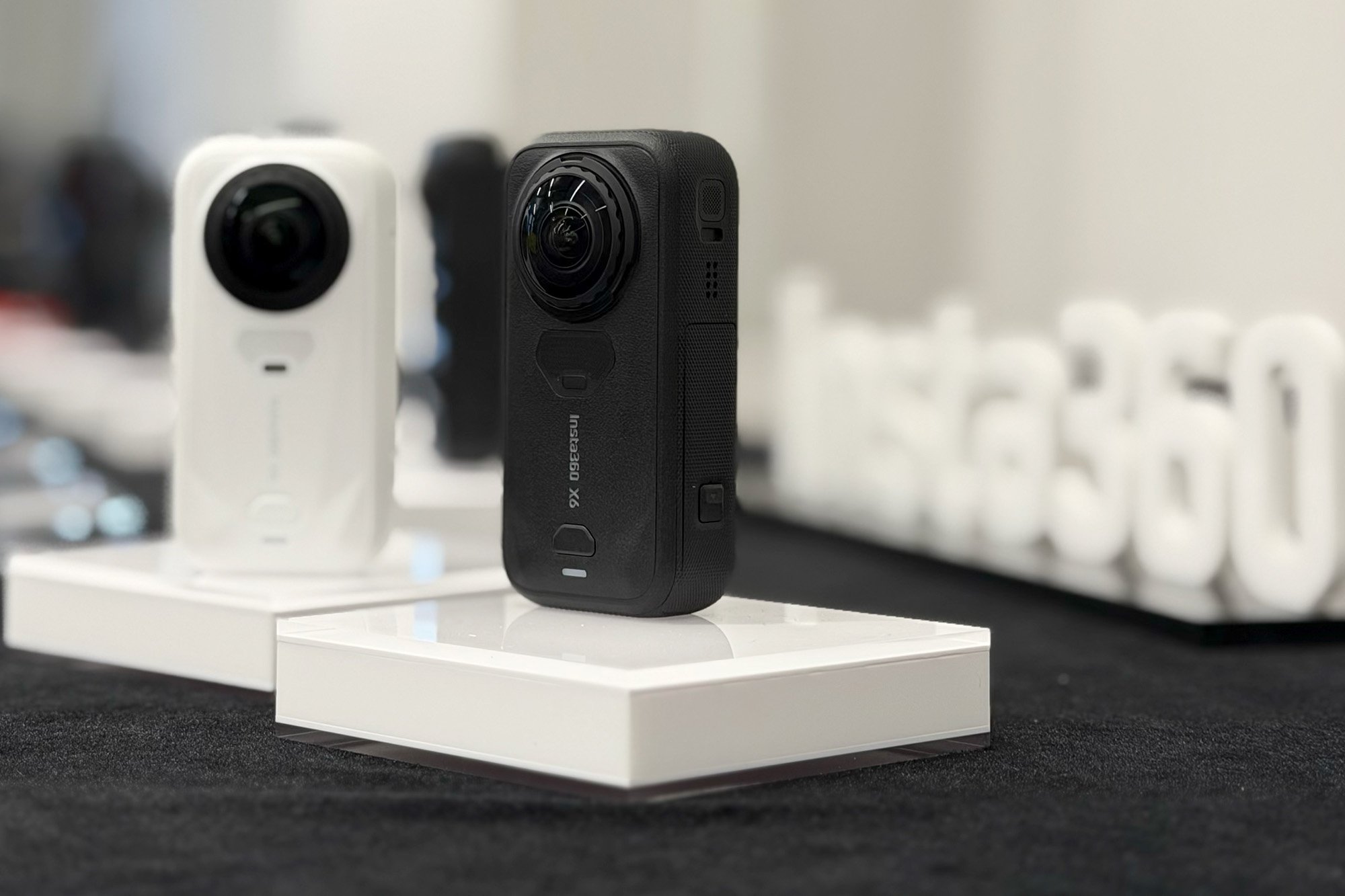 The Insta360 X6 camera in Black and White sitting on tiny pedestals on a table