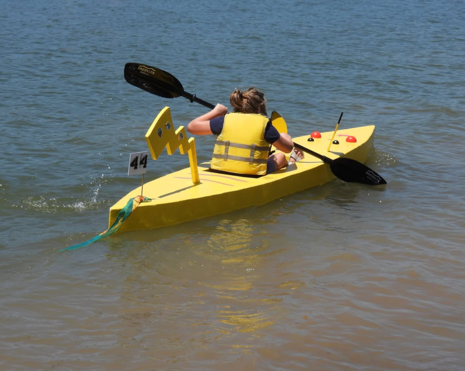 Woman paddling in cardboard kayak decorated like Pikachu from Pokemon