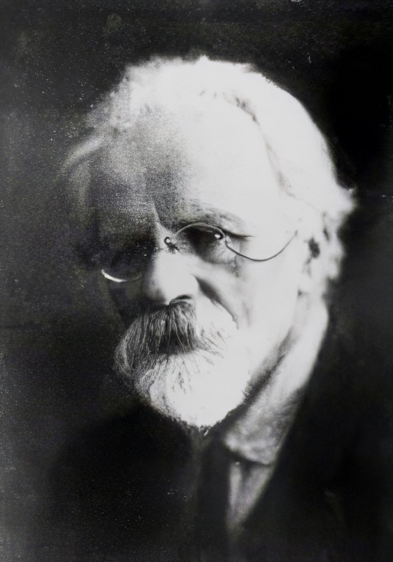 Black and white portrait of an elderly white man with glasses and a beard.