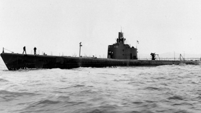 Black and white photo of the USS Trigger submarine at sea with crew standing atop it