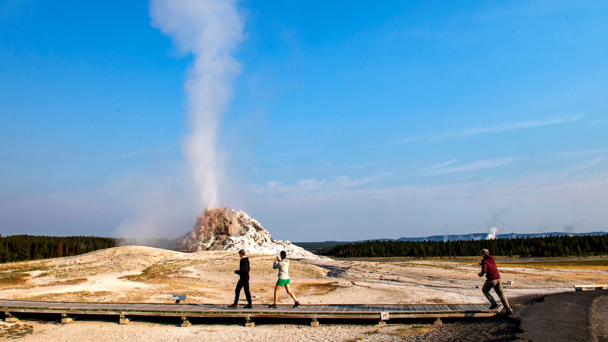 YELLOWSTONE NATIONAL PARK, WYOMING -AUGUST 7: Visitors walk the boardwalk as White Dome geyser erupts. The 12-foot-high geyserite cone is one of the largest in the park and has eruptions as tall as 30 feet on August 7, 2024 in Yellowstone National Park, Wyoming. (Photo by Jonathan Newton/Getty Images)
