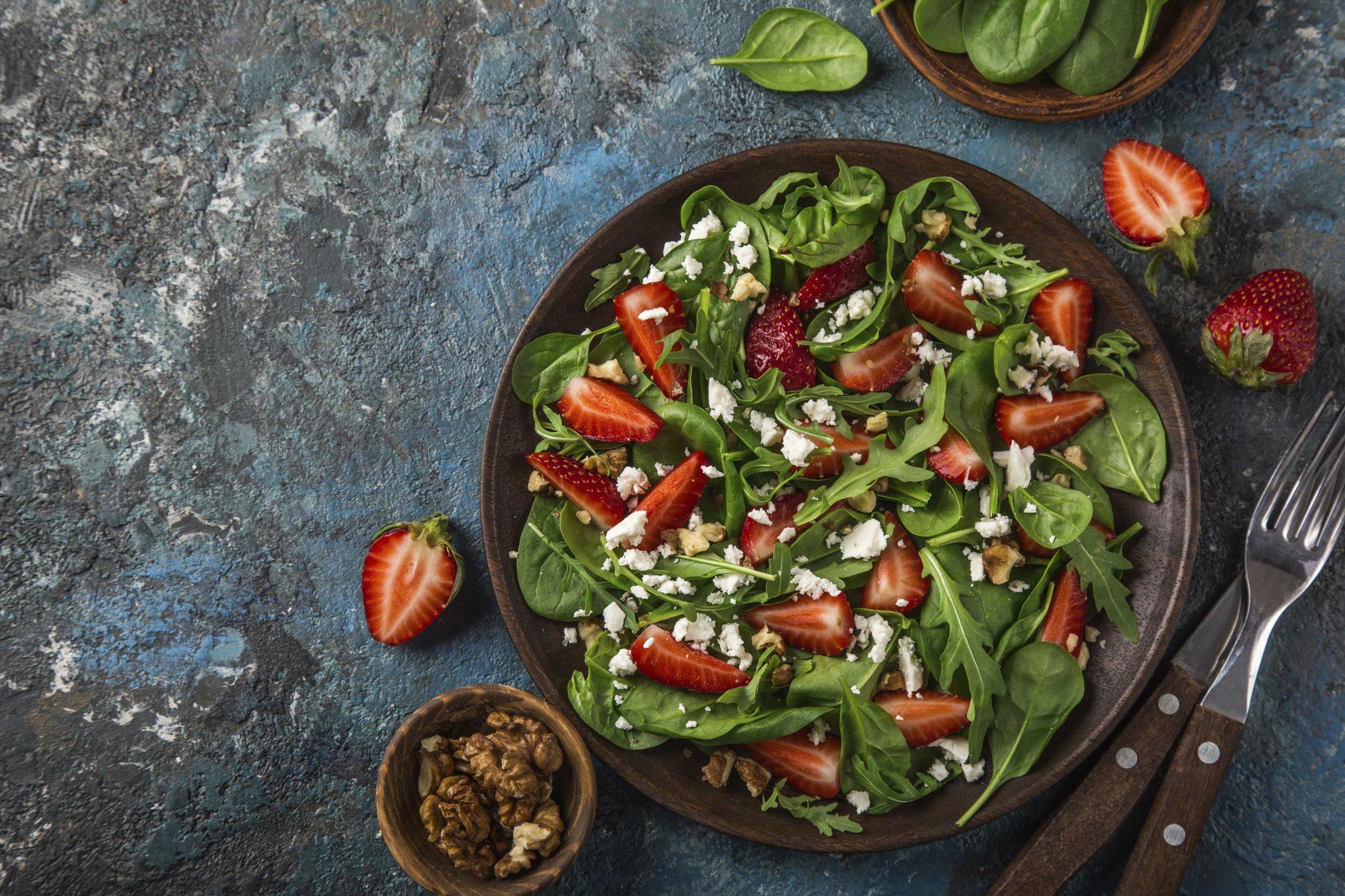 Strawberry, spinach, arugula and feta cheese salad, top view in bowl.