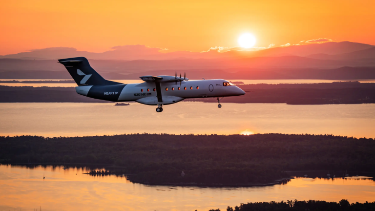 a white plane flies as the sun sets over a lake