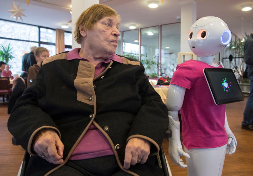28 November 2018, Hessen, Frankfurt/Main: Gisela Thoma, a resident of the old people's home, comes into close contact with the humanoid robot "Peppa" during an information event. As part of a project at the University of Applied Sciences Frankfurt, the students want to find out what senior citizens want from the robots so that they can perhaps one day be used in old people's homes. Photo: Boris Roessler/dpa (Photo by Boris Roessler/picture alliance via Getty Images)
