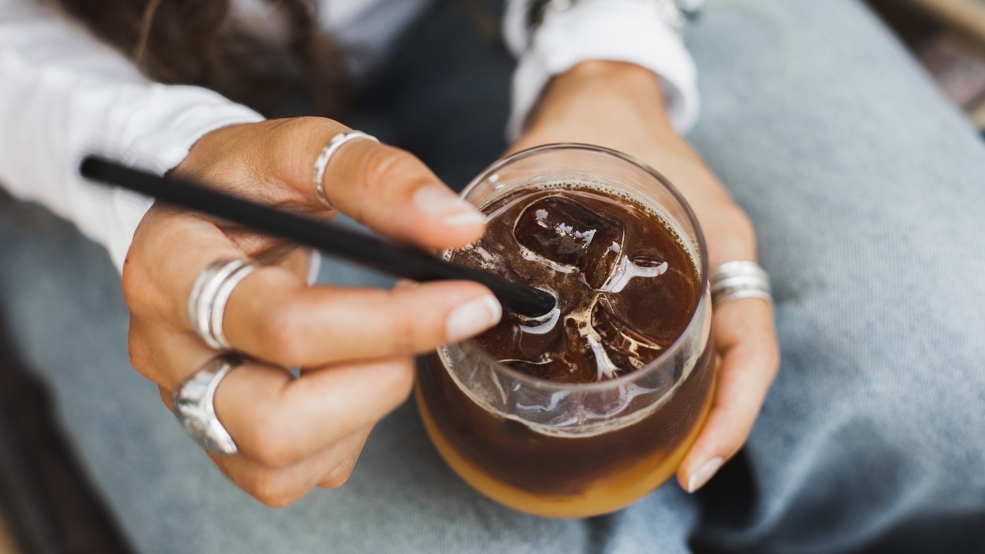 Woman holding in hands iced orange tonic or trendy bumble coffee. Youth culture.