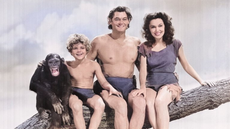 White woman, man, and child sitting on a tree branch in clothing made from scraps with a chimp.