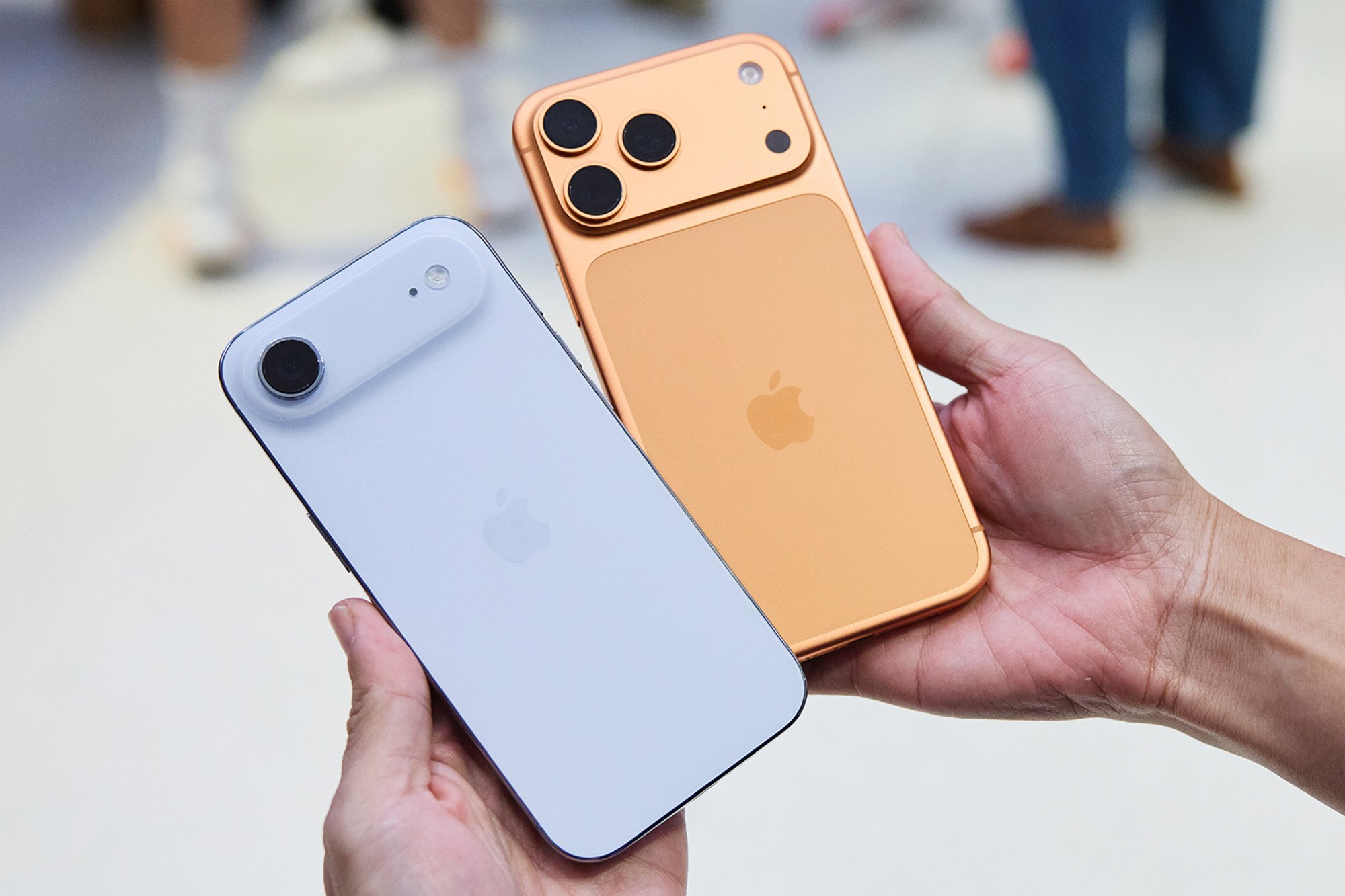 Hands holding two iPhone 17 models