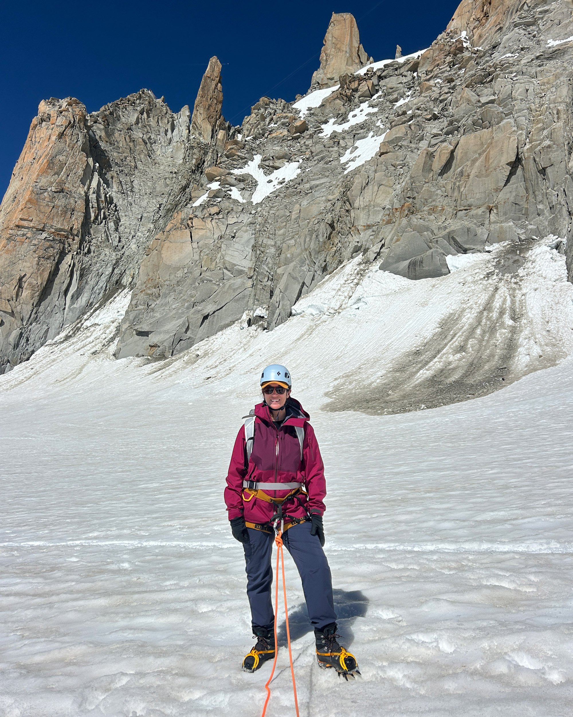 A woman wearing an arc'teryx jacket in front of a mountain on the French Alps