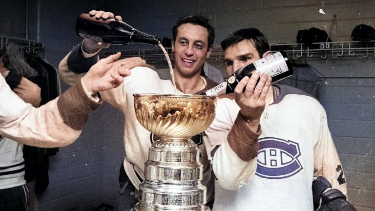 Two hockey players pour champagne into the stanley cup in a vintage colorized image.