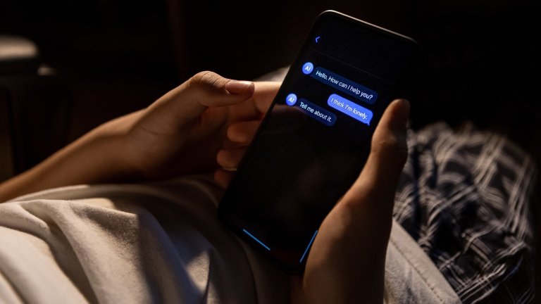 Teen holding smartphone with chat conversation on screen late at night at home. Scene represents digital communication, online interaction and private mobile messaging.
