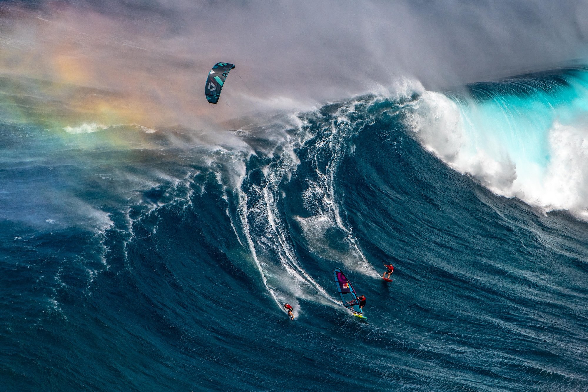 a surfer, windsurfer and kitesurfer sharing the same towering wave