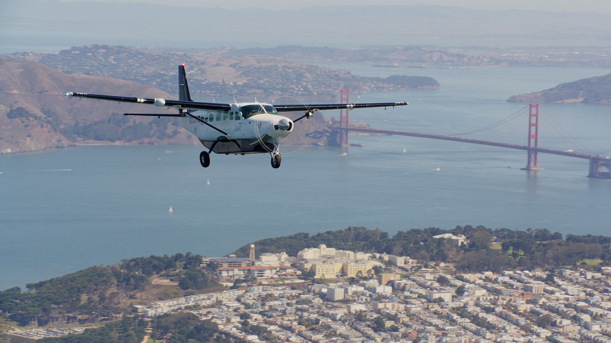 Cessna airplane flying in San Francisco with the Bay Bridge seen in the background
