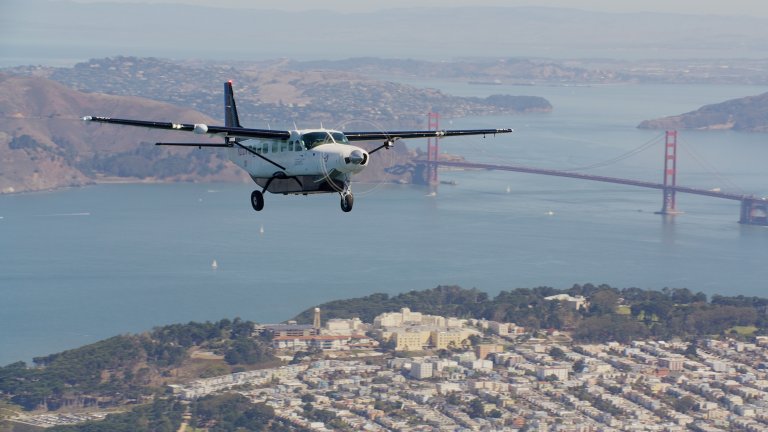 Cessna airplane flying in San Francisco with the Bay Bridge seen in the background