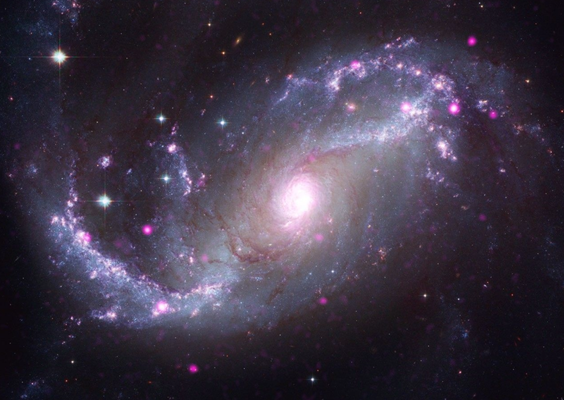 A barred spiral galaxy featuring a prominent central bar or bridge of stars that channels gas toward its core. Chandra X-rays (purple) highlight growing black holes along the bar and core, merged with Hubble optical light (white, yellow and soft blue) and JWST infrared dust filaments (red). Studying barred spirals in action can help reveal how gas in our own Milky Way, which is also a barred spiral, feeds its central black hole and forms new stars. Image X-ray: NASA/CXC/SAO; Optical: NASA/ESA/STScI/Hubble Heritage Team; Infrared: NASA/ESA/CSA/STScI/J. Lee and T. Williams; Image Processing: NASA/CXC/SAO/L. Frattare, J. Major, K. Arcand.