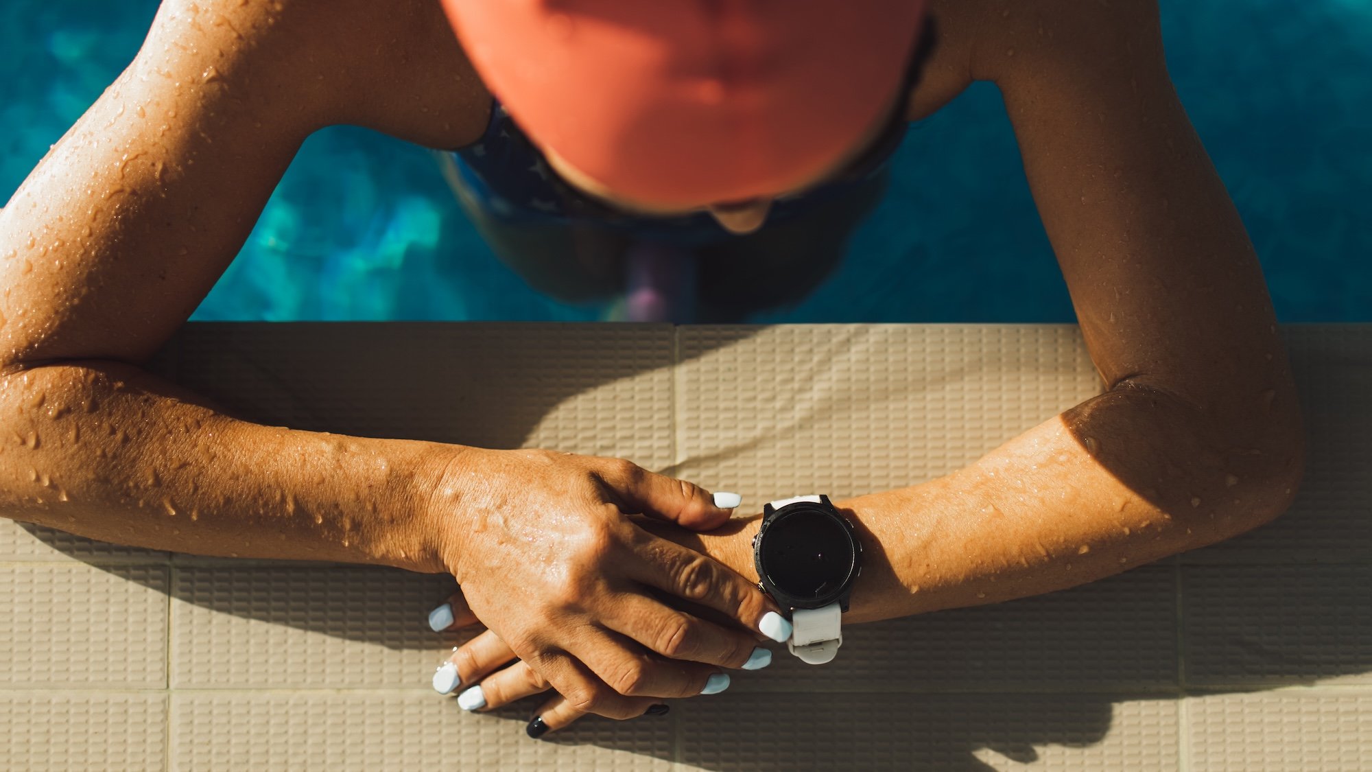 Woman resting in pool with arms crossed to show smartwatch