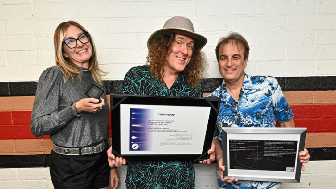 Dr. Allison McGraw, Al Yankovic, AND Dr. Steve Desch. stand against a wall. Al is holding a framed certificate