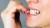 nervous young woman biting her nails on gray background