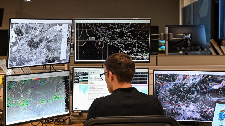 Tropical analysis meteorologist Aidan Mahoney works at his station at the National Oceanic and Atmospheric Administration's (NOAA) National Hurricane Center in Miami, Florida, on May 30, 2025. The administration of US President Donald Trump has fired hundreds of staff at the National Oceanic and Atmospheric Administration (NOAA) and deleted government websites with data on the weather and climate. (Photo by CHANDAN KHANNA / AFP)