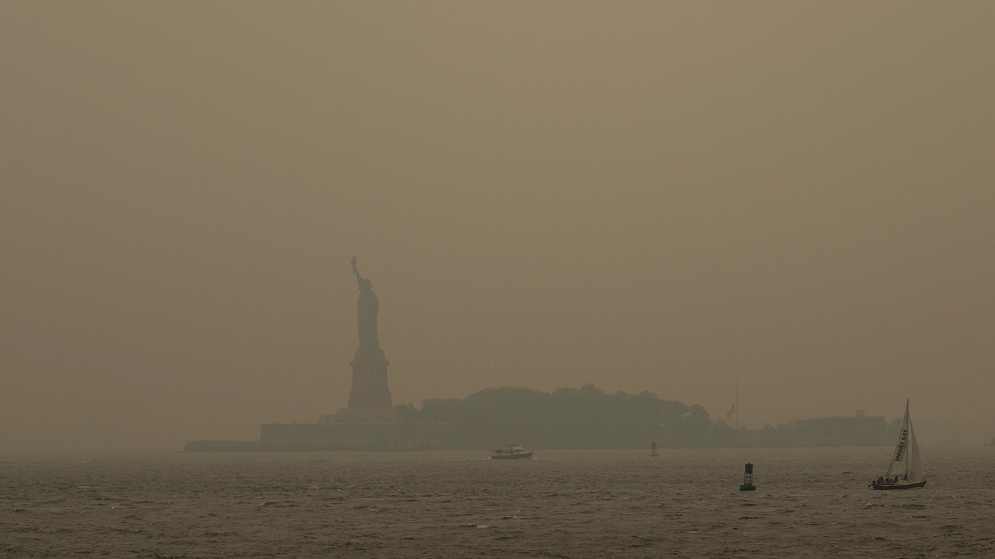 NEW YORK, NEW YORK - JULY 16: Haze from Canadian wildfires blankets the Statue of Liberty as seen from a Staten Island Ferry on July 16, 2026 in New York City. Much of the East Coast and Canada is under an Air Quality Health Advisory as the Canadian and Great Lakes wildfire smoke gradually moves through the area, creating a thick haze in the heat. The region is experiencing temperatures with heat indexes over 100 degrees as it confronts another heat wave. (Photo by David Ramos/Getty Images)