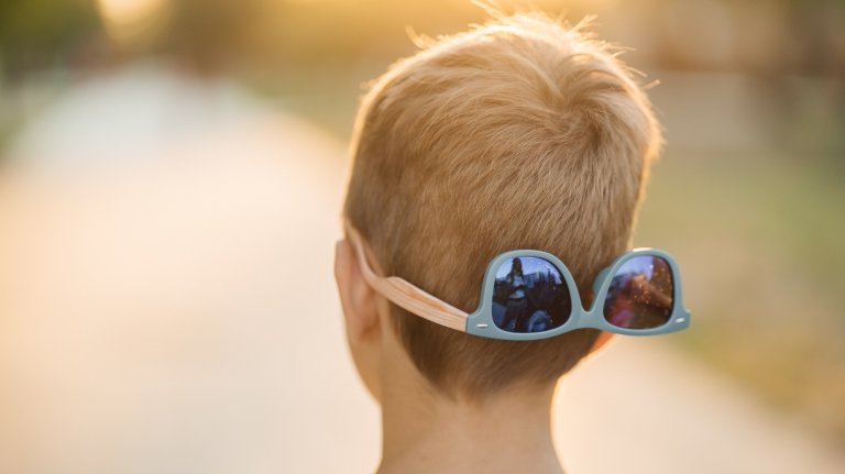 child put glasses on the back of his head, back view