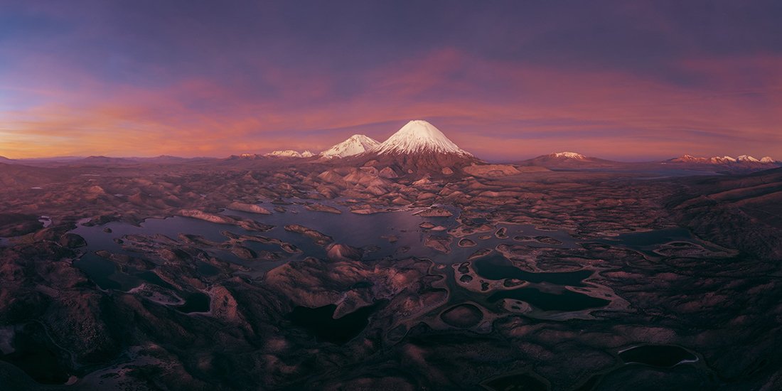 rose-colored sky above lakes and snow-capped peaks