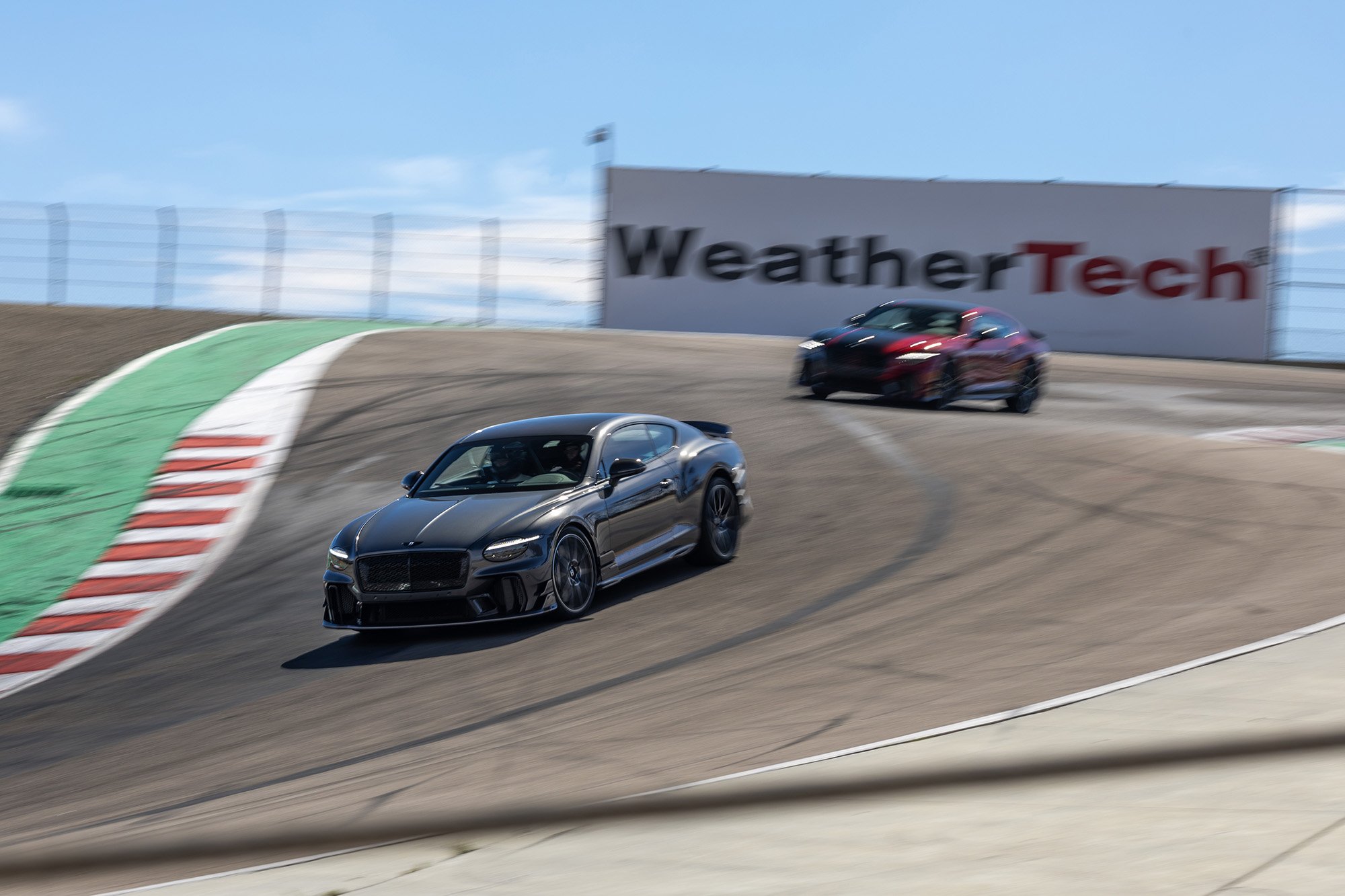 A Bentley 2026 Supersports car shown in Anthracite, drifting in front of another car on a racetrack in Monterey, California.
