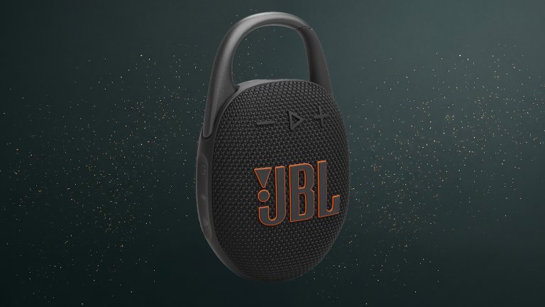 JBL Clip 5 Bluetooth speaker on a green sparkly travel gift guide background