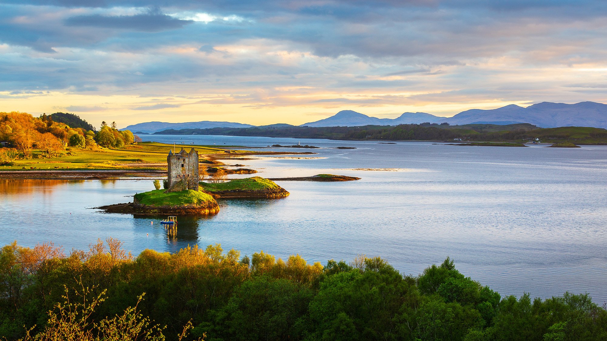 Castle ruins on small island in dramatic landscape photograph.