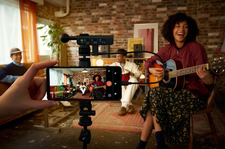 A picture of someone recording their friends performance on a smartphone with the new Sony ECM-AX10 spatial USB-C microphone attached