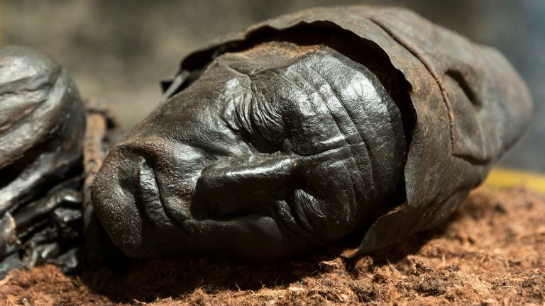 Close up of a head of a bronze-looking older man in a cap with his eyes closed.