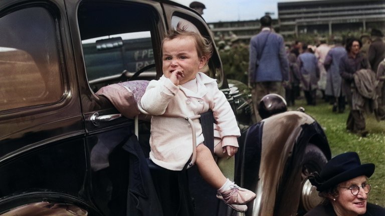 Baby car seat on outside of car in vintage, colorized photograph.